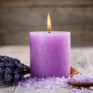 Hand-poured Lavender Candle in a glass jar surrounded by fresh lavender sprigs.