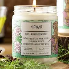 Hand-poured Nirvana Candle glowing softly beside stones and incense in a tranquil setting.